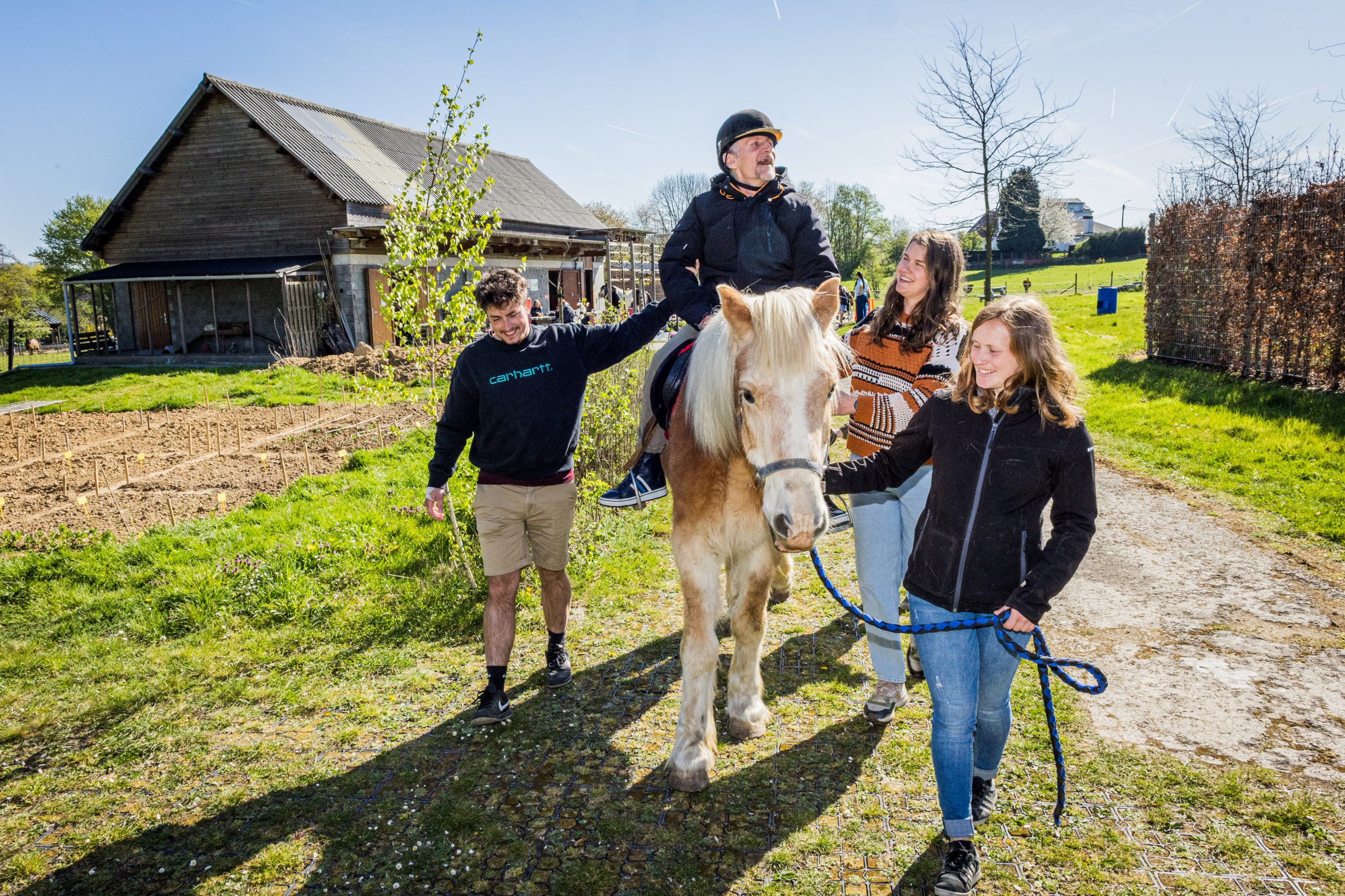 Drie begeleiders begeleiden een zorgvrager per paard